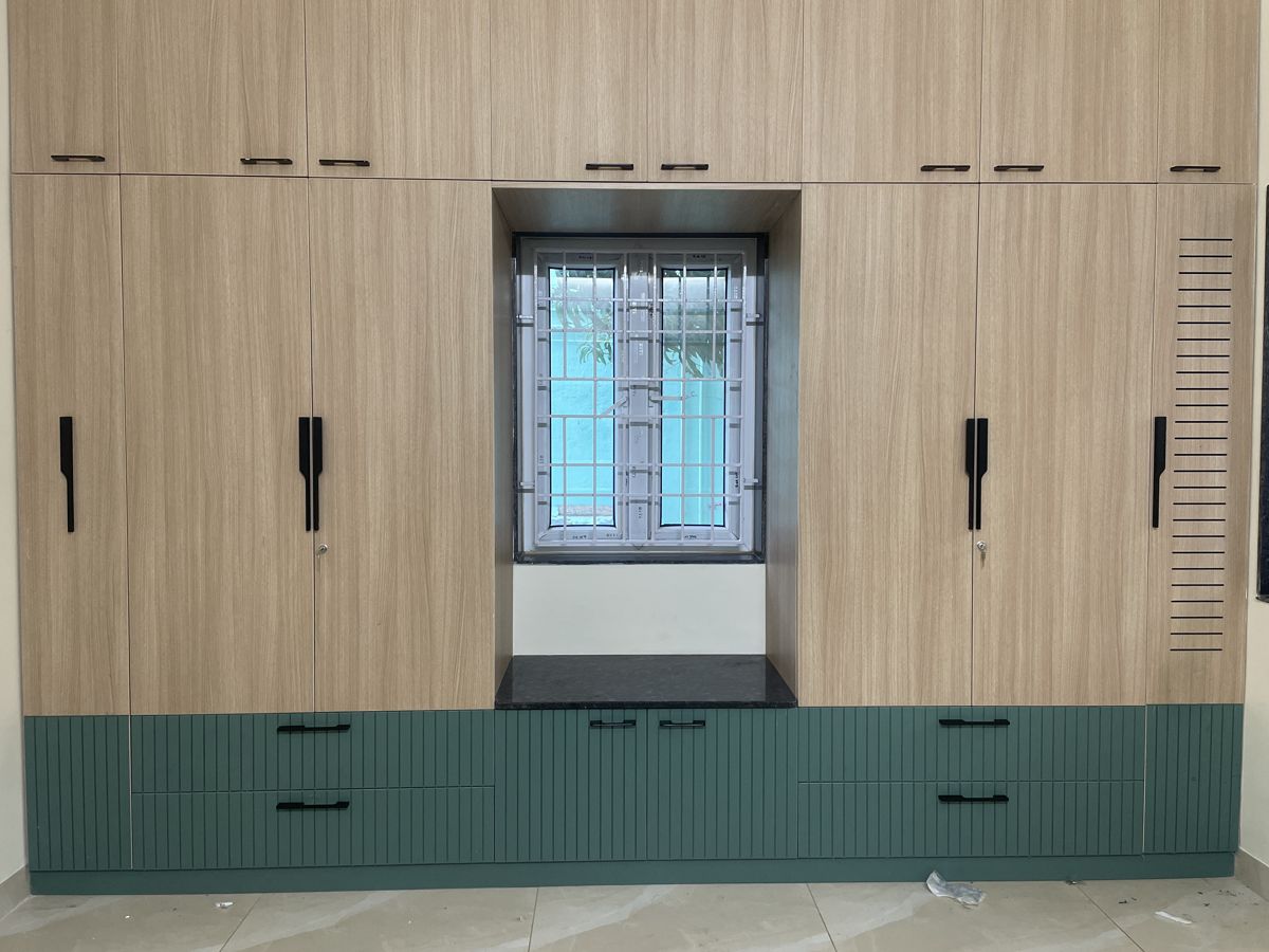 Green wardrobe beside a bright window in a Chennai bedroom